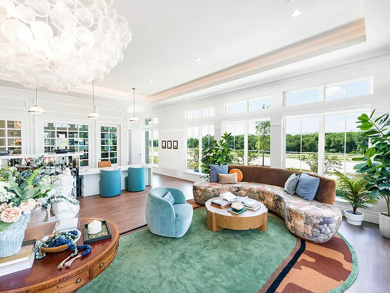 Sunlit leasing office with expansive windows, curved seating, and layered textures that frame green views and invite you home.