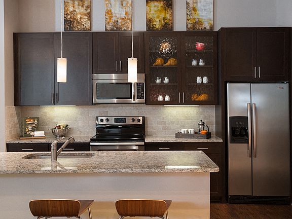 Gourmet kitchens feature granite or quartz countertops with natural stone backsplash