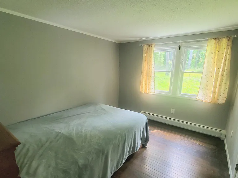 A bedroom with a queen size bed (wooden headboard with storage), closet
