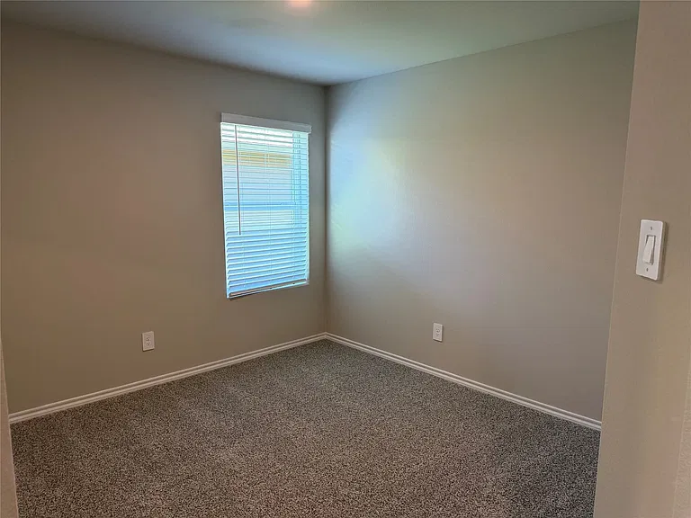 Neutral-toned walls complement the textured gray carpeting