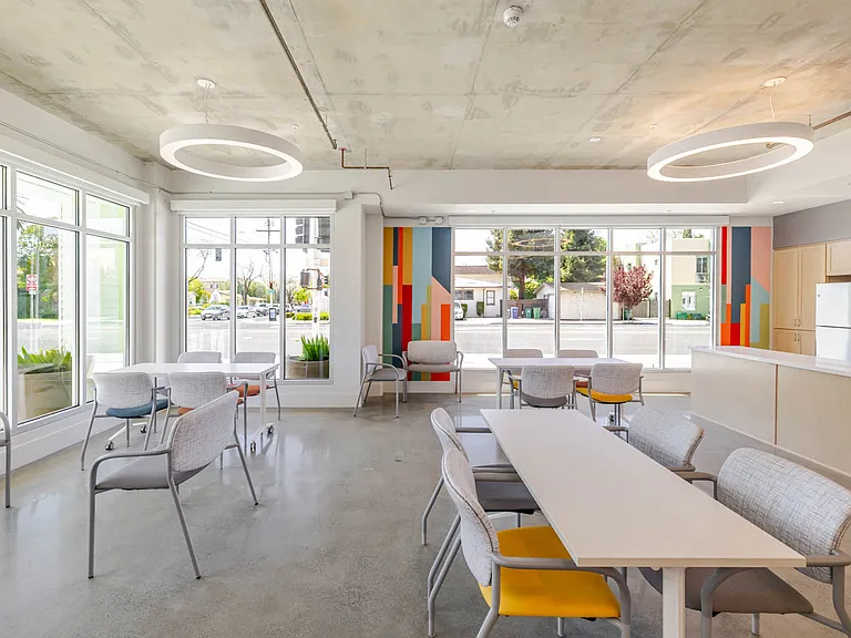 Community room with flexible seating and adjacent kitchen for gatherings.