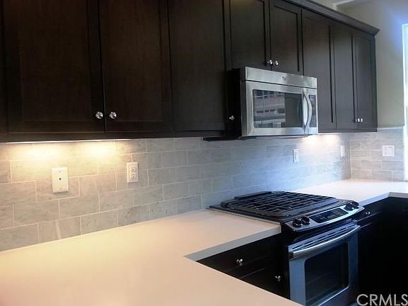 Kitchen cabinets are dark maple w stone countertops and stainless appliances