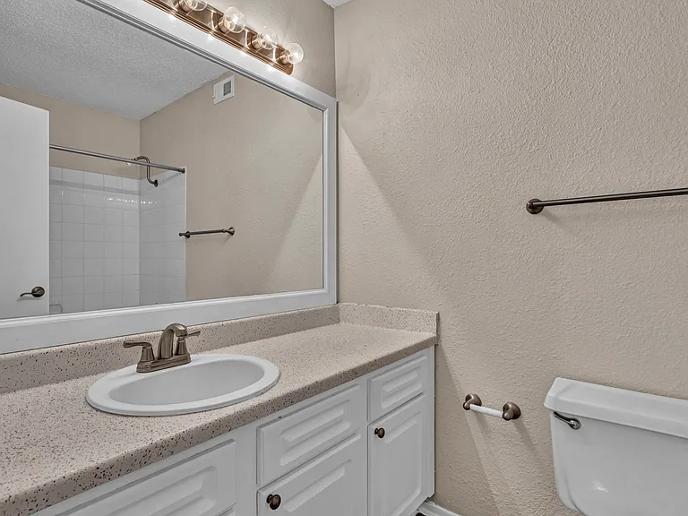 Bathroom with large mirror, updated vanity, and modern lighting.