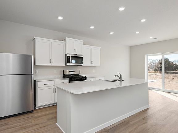 The kitchen has stainless steel appliances and plank flooring,