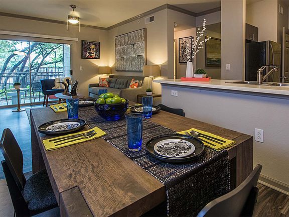 Apartment Kitchen with Stainless Steel Appliances, Dining and Living Room with wood floors.