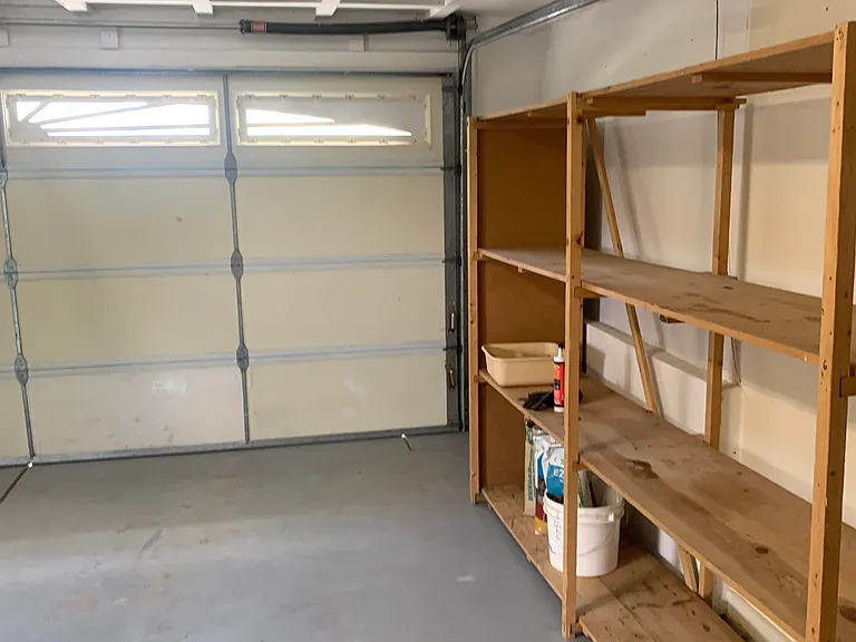 Garage with full-wall shelves and storage above garage door