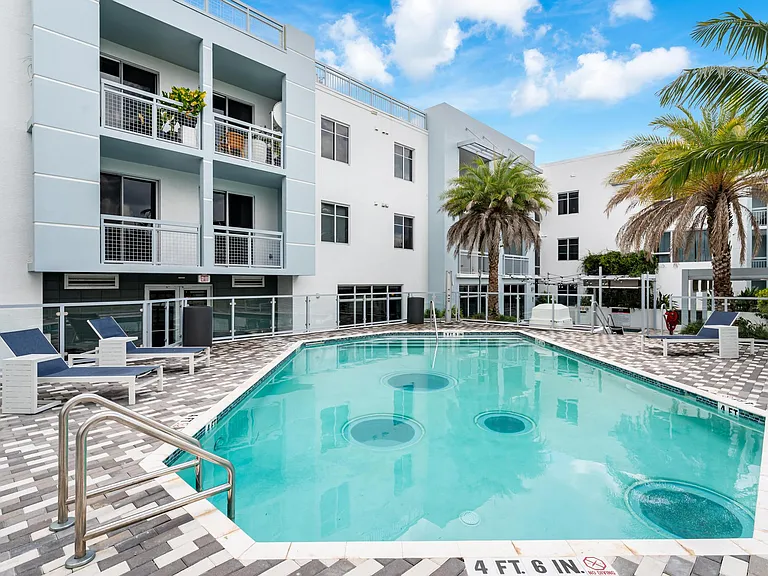 Pool Area Surrounded by Palm Trees and Chaise Seating