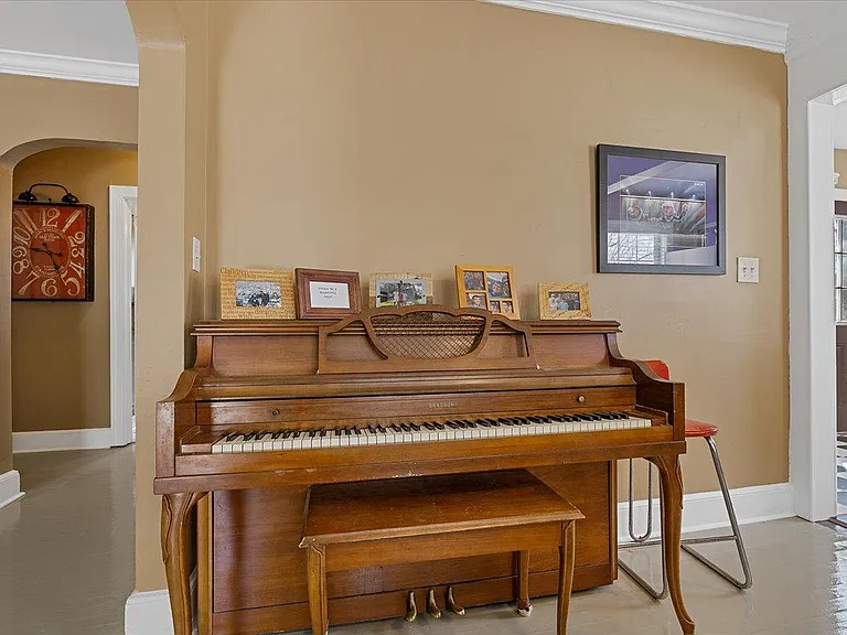 Dining room at Hunsucker's Place features a piano and a view into the kitchen. Located within walking distance of Cone Health Hospital and Downtown Greensboro, this space is perfect for enjoying meals and music in a cozy, central location.