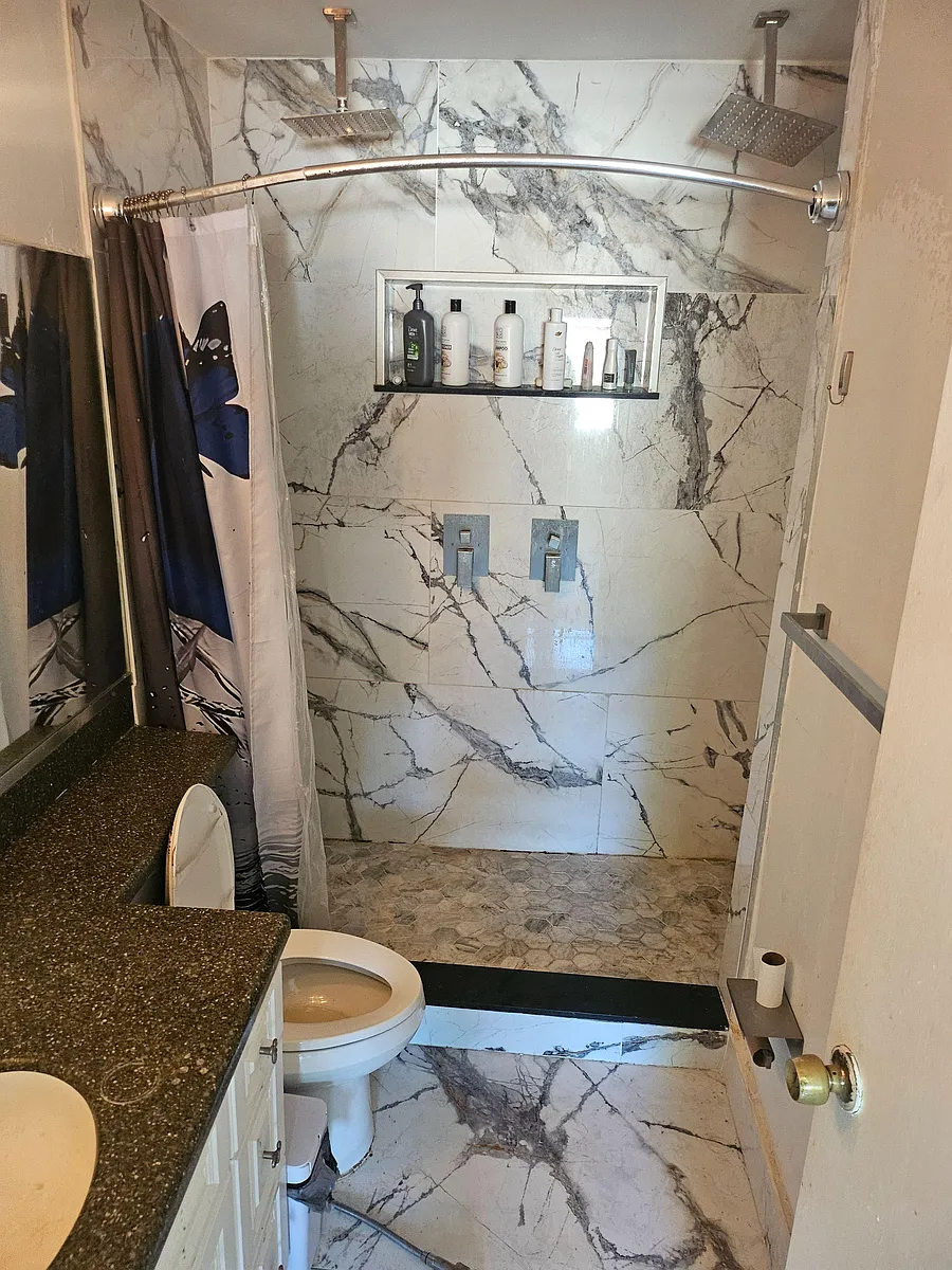 Full bathroom with tiled shower surround, dual rainfall showerheads, and a built-in niche for toiletries. - S Meadowview Cir