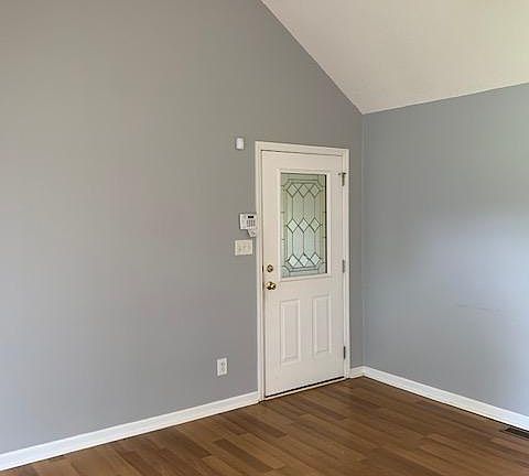 Living room with cathedral ceiling and ceiling fan. Door is entry into double garage.