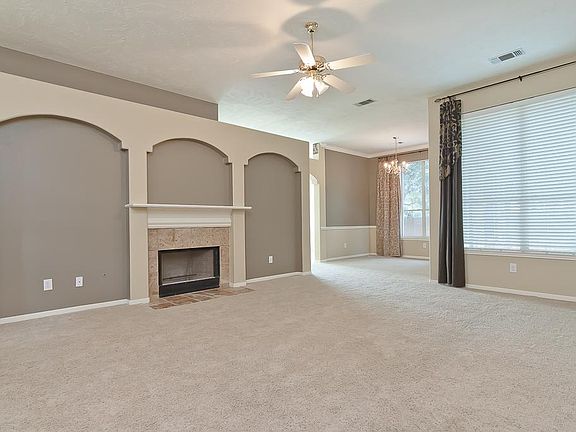 The living room boasts a dramatic wall of recessed arches with a beautiful centered fireplace with a white painted mantel, ceramic tile surround and tiled hearth.  The ledge above this walls provides additional decorating possibilities.