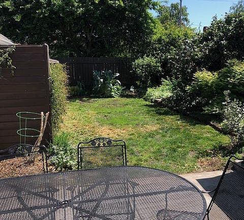 Back patio looking out at yard-comes with wrought iron furniture set. To the right is a large shed for storage. To the left is an ADU behind privacy wall.