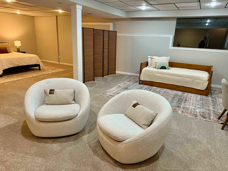 In the basement, there is a twin trundle, queen size bed, workspace and comfortable seating area. This allows for an extra living space for game night and room to enjoy the larger private space.