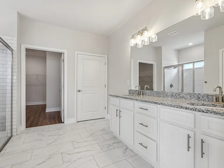 Primary bathroom with double vanity, walk-in shower and walk-in closet.