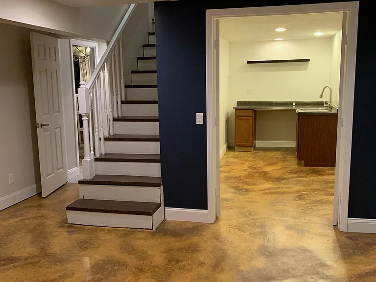 Finished basement view into kitchenette/craft room. Hallway on left goes to second bathroom.