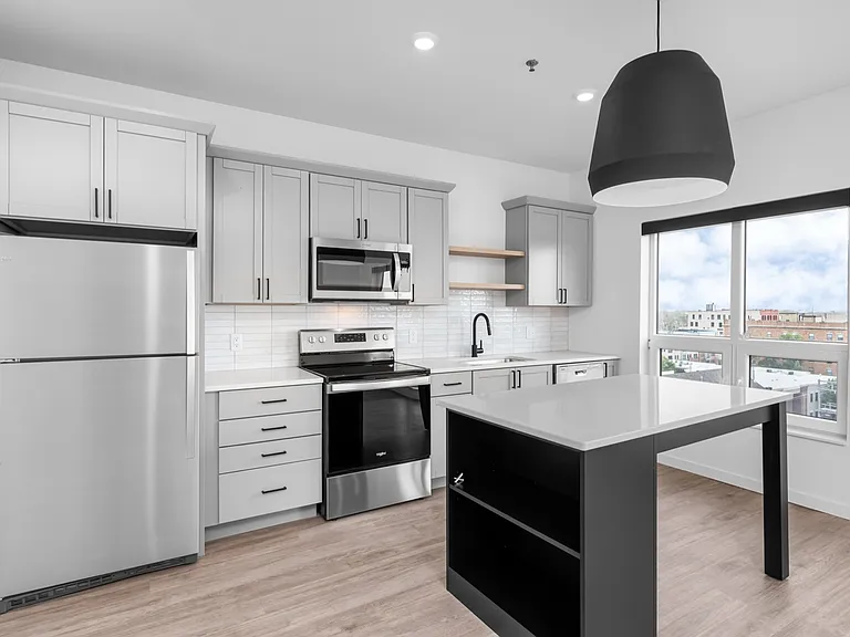 Modern kitchen with sleek stainless steel appliances, bright cabinetry, and a large island with built-in shelving, featuring abundant natural light from expansive windows. Modern kitchen with sleek stainless steel appliances, bright cabinetry, and a large