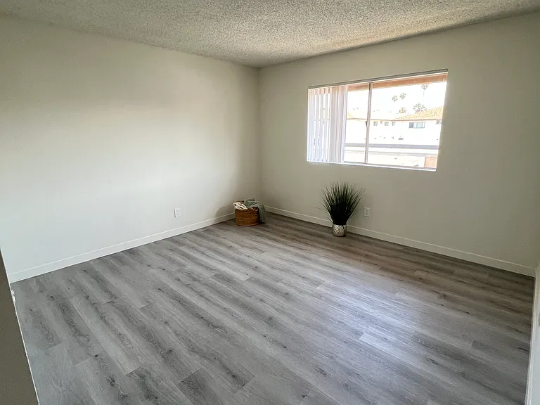 The bedroom with wood-like floor and large window
