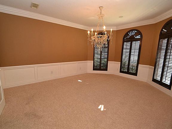 Dining room enhanced by crown molding, chair rails, bay window with plantation shutters and access to the kitchen.