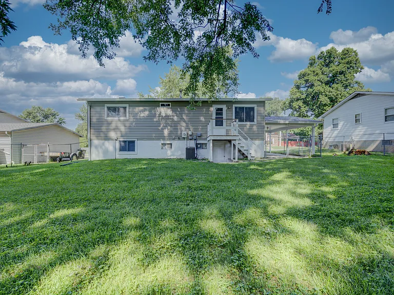 View of the rear of the home - showing the deck, walkout door, and carport.