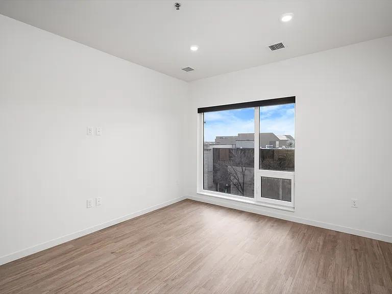 Bright, modern room with hardwood floors and a large window offering an urban view. Bright, modern room with hardwood floors and a large window offering an urban view.
