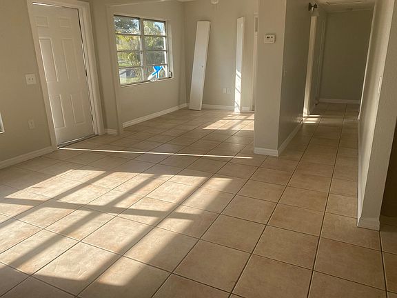 Part of the living room and dining room with hallway leading to two of the bedrooms and bathroom.