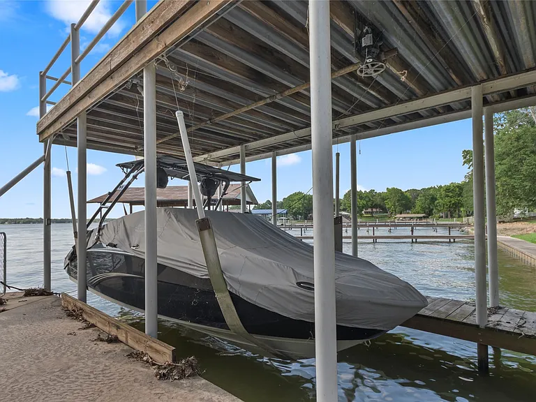 Covered boat dock featuring a boat lift, corrugated metal roof, and a wood decking upper level