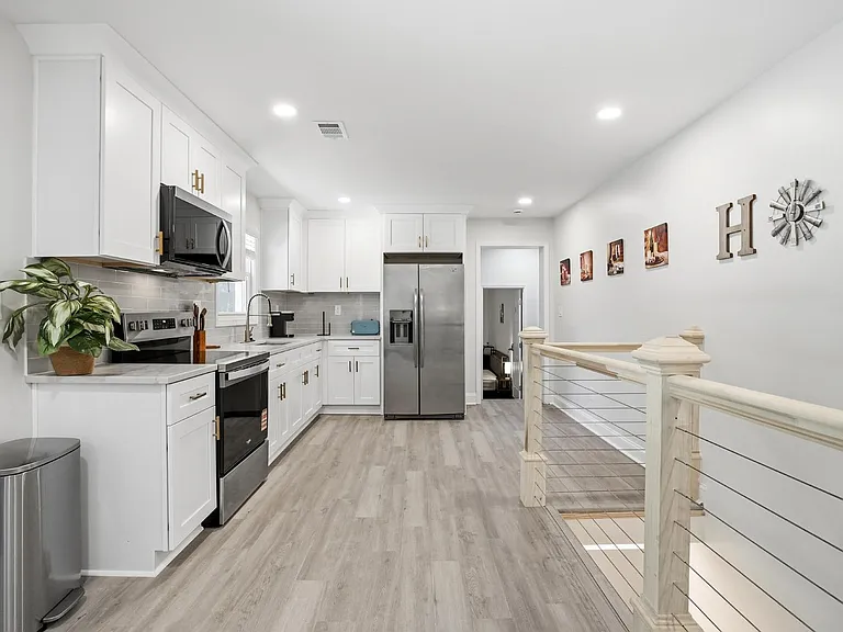 Open kitchen with white cabinetry, ample counters, and stainless-steel appliances including a side-by-side fridge.