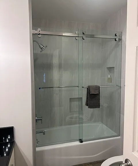 Guest bathroom shower/tub. Newly remodeled with frameless sliding glass doors