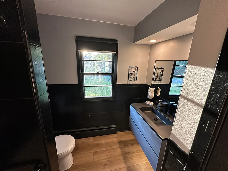Main floor bathroom features half tiled walls, new toilet and floating vanity with underlighting.