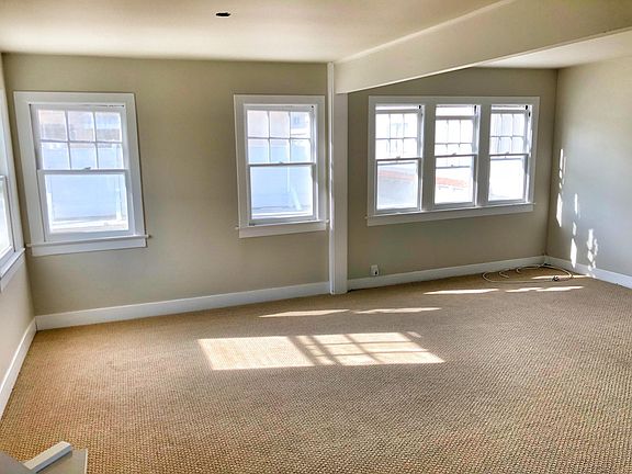 Sunny living area with large windows and soft neutral finishes.