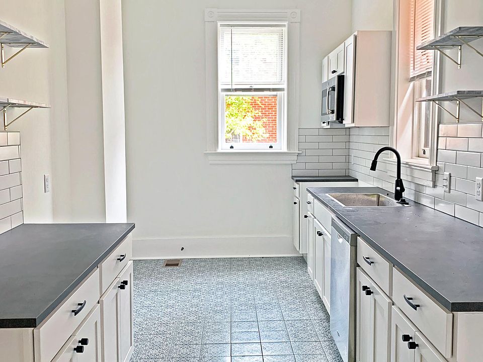 Galley kitchen with beautiful patterned floor tile, marble floating wall shelves, and new appliances. 
*Refrigerator and range have now been installed*