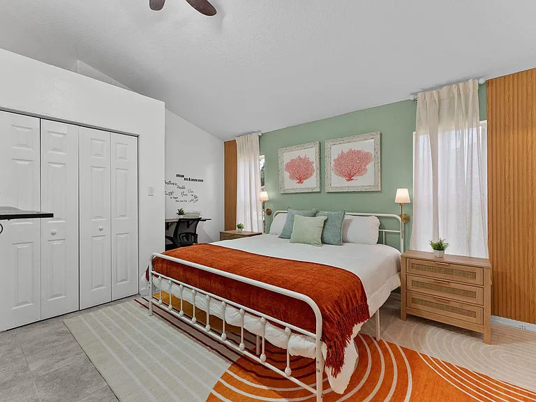 Spacious bedroom with a queen bed, dual windows, nightstands, and a large closet plus a dedicated desk nook.