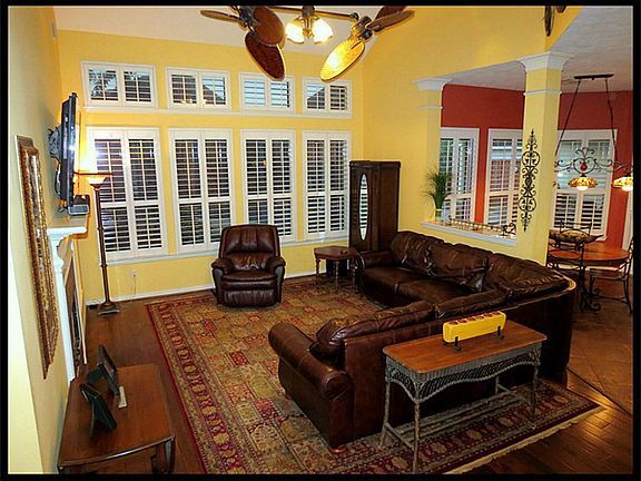 2 story family room with beautiful dual palm ceiling fan. Wall of windows overlooking the pool.