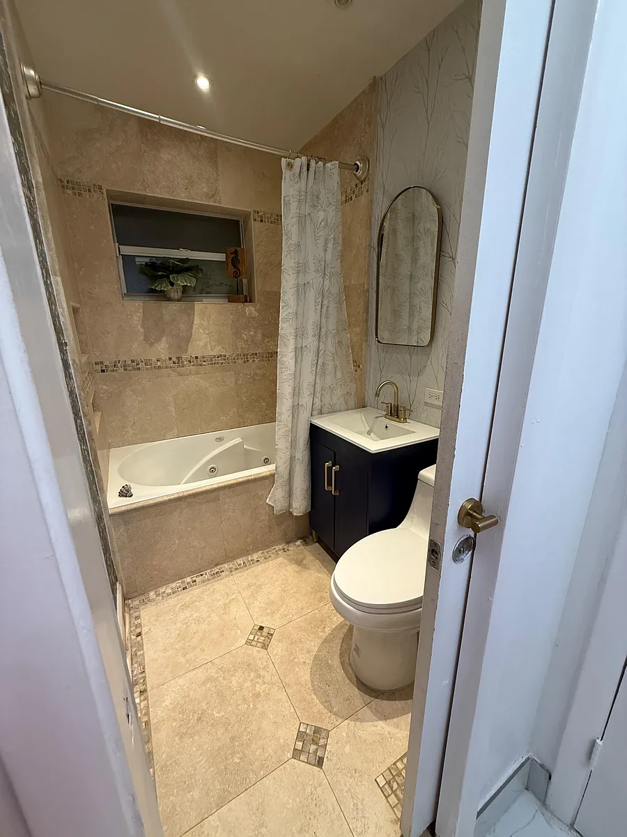 Tiled bathroom with a tub/shower combo, updated vanity, and a wall mirror, plus a small window for ventilation. - SW 2nd Ave