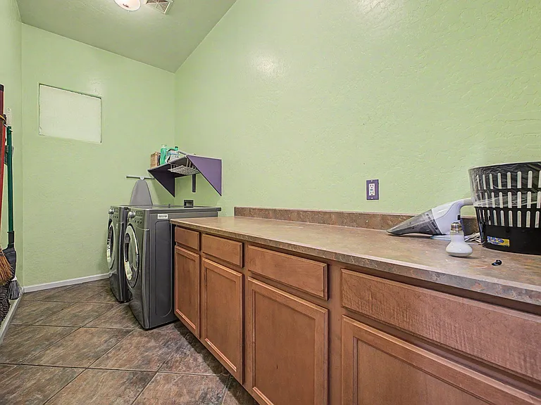 Dedicated laundry room with front-load washer/dryer, long folding counter, and ample base cabinetry for storage.