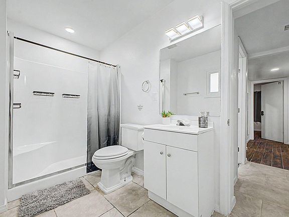 Clean full bath with tub/shower combo, oversized mirror, and vanity storage with easy-care tile flooring.