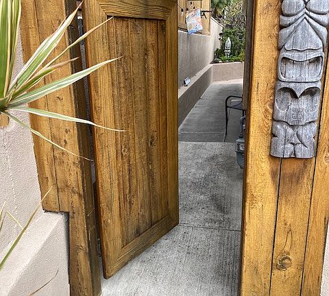 Gate to the side of the house and back yard. Light tiki decor. New fencing.