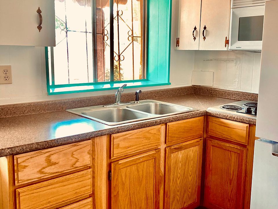 Full kitchen with upper and lower cabinets, built in microwave, full-size refrigerator, electric stovetop, tile floors, east morning window, and door to the back patio.