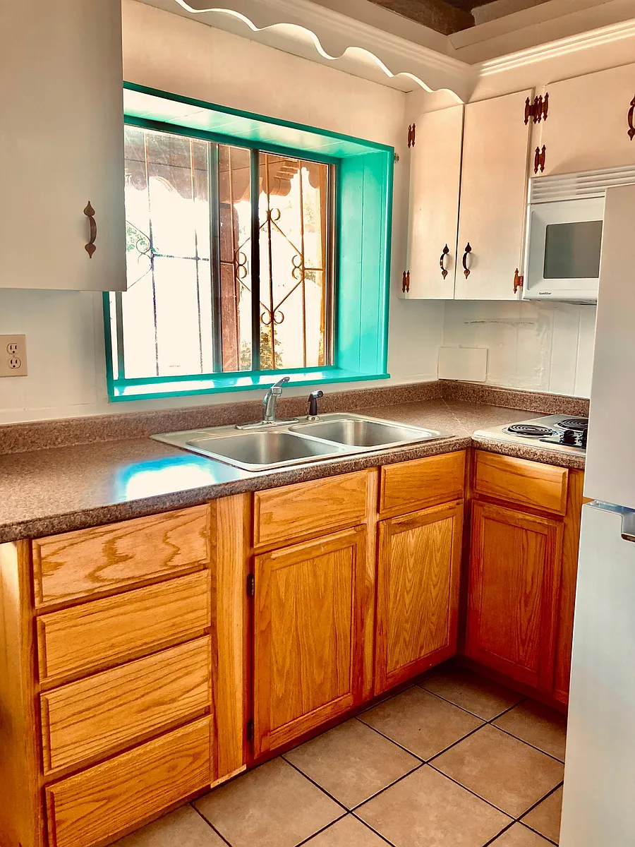 Full kitchen with upper and lower cabinets, built in microwave, full-size refrigerator, electric stovetop, tile floors, east morning window, and door to the back patio. - 601 Gomez Rd #C