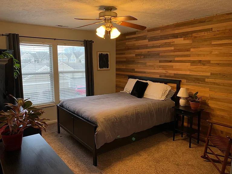 Spacious master bedroom with a gorgeous maple wood accent wall and ensuite bathroom.