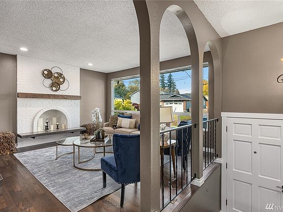 Inviting and warm entry and living room with arched openings and white painted brick fireplace.