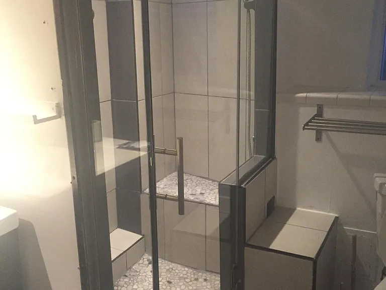 Bathroom shower with rain fall shower, body jets, and a separately pressured handheld with seated bench area in the shower.
