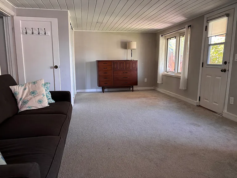 entering living room/bedroom from kitchen+ room, second doorway to outside on right wall