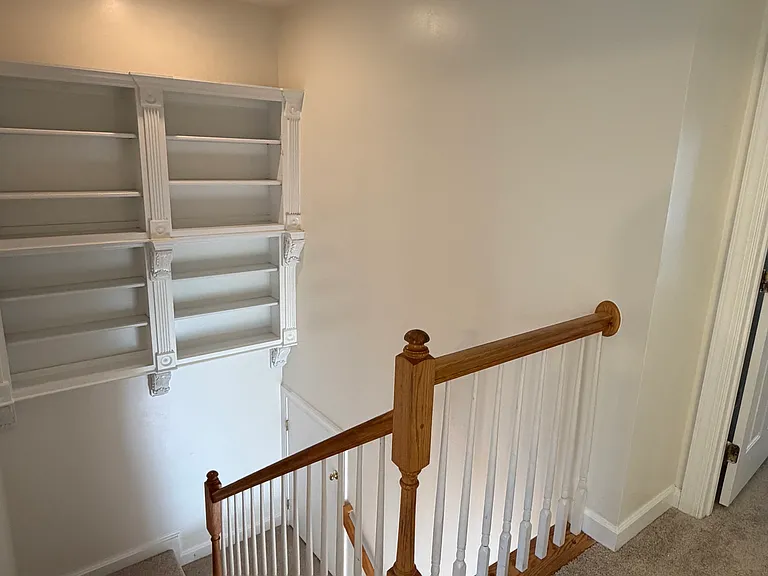 Top of the stairs looking at built in shelves. Owners suite to the right, hall bath behind, two bedrooms to the left