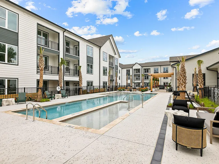 Modern apartment pool with tanning ledge, outdoor lounge seating, and resort-inspired community amenities.