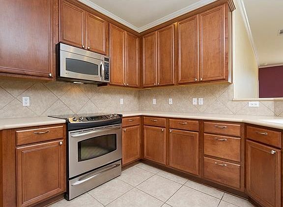 Kitchen has high cabinets with hardware plus stainless appliances.