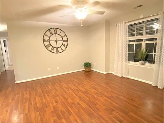 Huge great room has beautiful wood laminate flooring, neutral light grey paint and lots of natural light