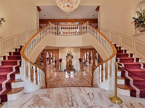 Impressive front doors open into a light-filled double-height foyer with elegant curved stairs..