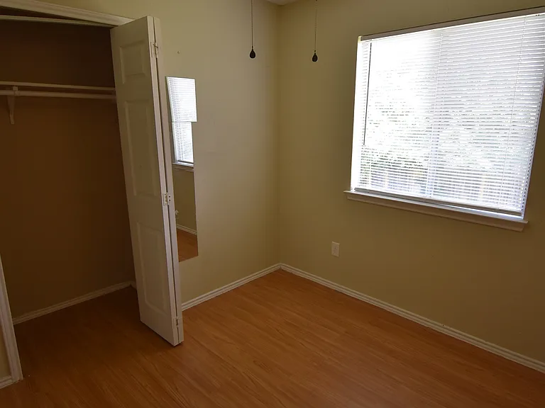 Different view of the same guest bedroom with a ceiling fan and a large window