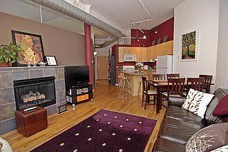 Spacious living area w/fireplace, soaring ceilings & exposed brick